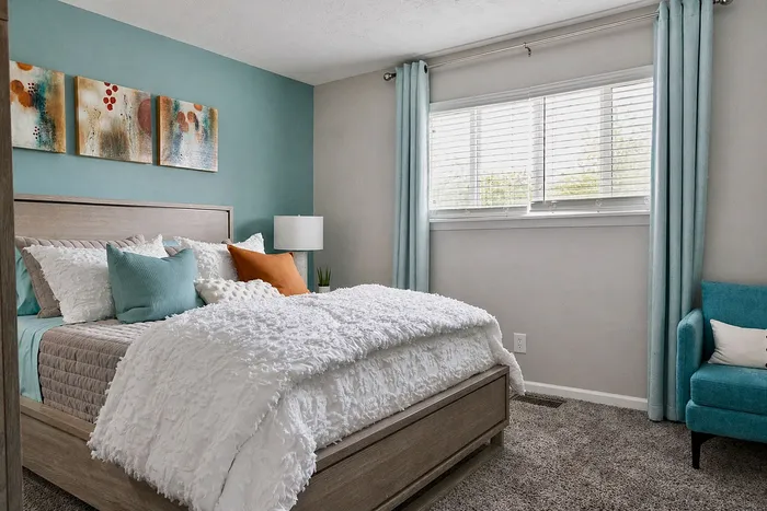 Cozy bedroom with modern teal accents, featuring a plush bed, colorful pillows, and serene wall art.