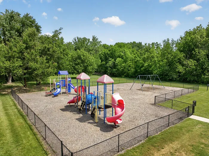 Vibrant playground with colorful slides and swings surrounded by lush greenery, perfect for family fun and outdoor activities.