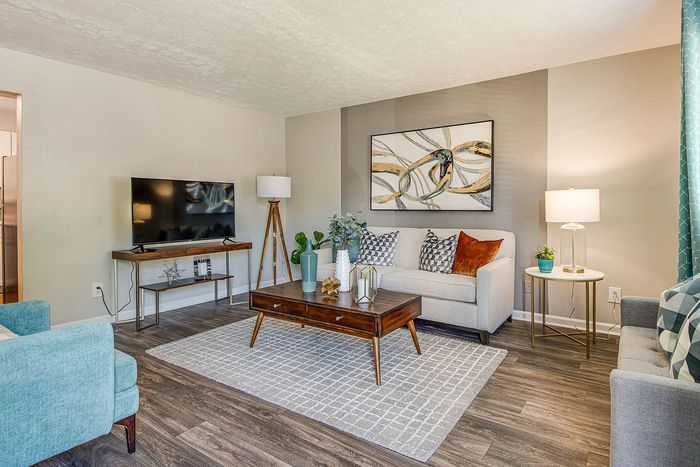 Inviting living room with modern decor, featuring a stylish sofa, elegant artwork, and a sleek television setup.