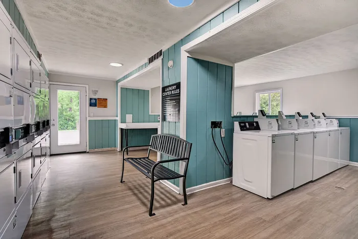 Bright and airy laundry room with modern appliances, fresh teal and white decor, and convenient seating.