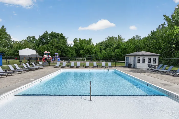 Inviting outdoor pool area with comfortable loungers and lush greenery, perfect for relaxation and family fun.