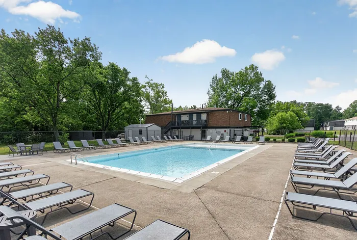 Inviting outdoor swimming pool area with stylish lounge chairs and lush green surroundings, perfect for relaxation and leisure.