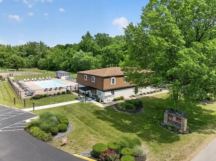 Attractive apartment complex with a shimmering pool, surrounded by lush greenery and a welcoming community area.