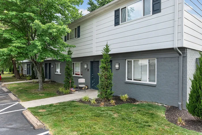 Charming townhouse exterior with modern gray brick design, surrounded by lush greenery and a well-maintained lawn.