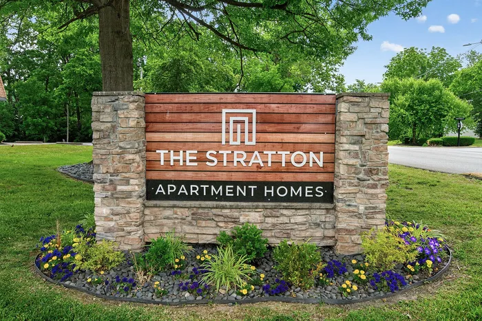 Inviting entrance sign for The Stratton Apartment Homes, surrounded by lush greenery and vibrant floral landscaping.