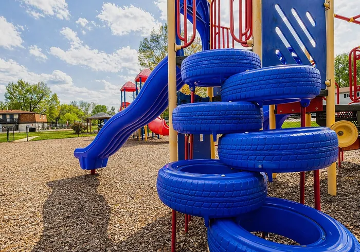 Inviting playground with vibrant blue slides and tire climbing structure under a sunny sky, perfect for family fun.