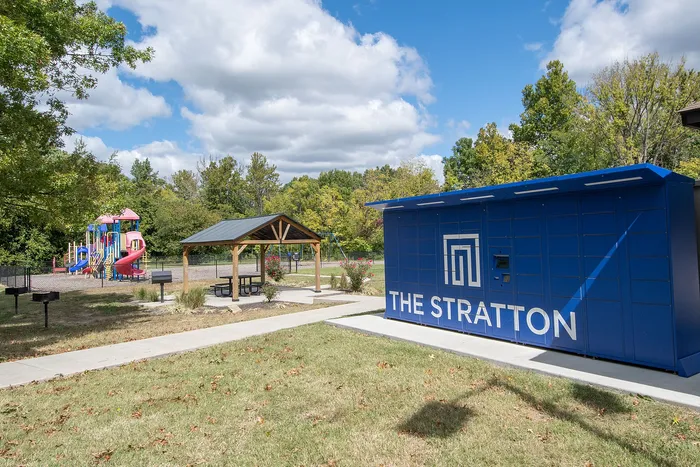 Charming outdoor space at The Stratton with vibrant playground and cozy picnic area, surrounded by lush greenery.