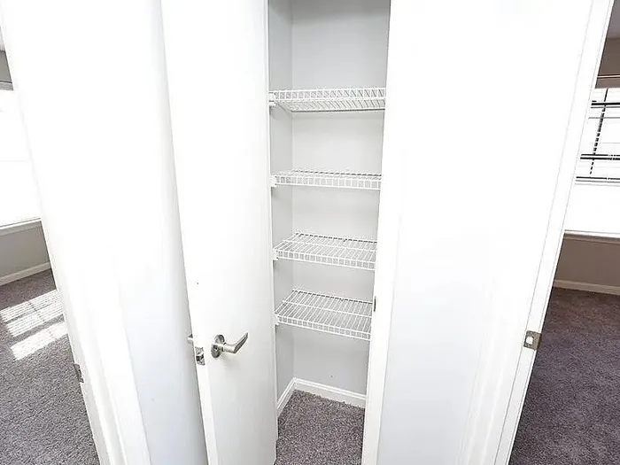 Bright and airy closet space with sleek white shelving, perfect for organized storage in a modern apartment.