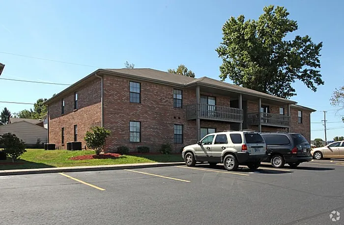 Charming brick apartment building with well-maintained landscaping and ample parking in a peaceful neighborhood setting.
