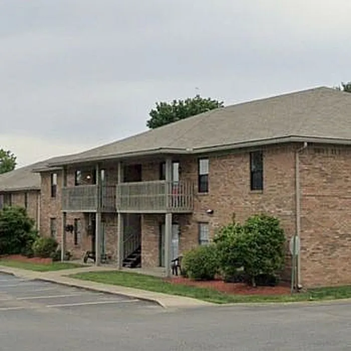 Charming brick apartment complex with lush greenery and inviting balconies, perfect for serene living.