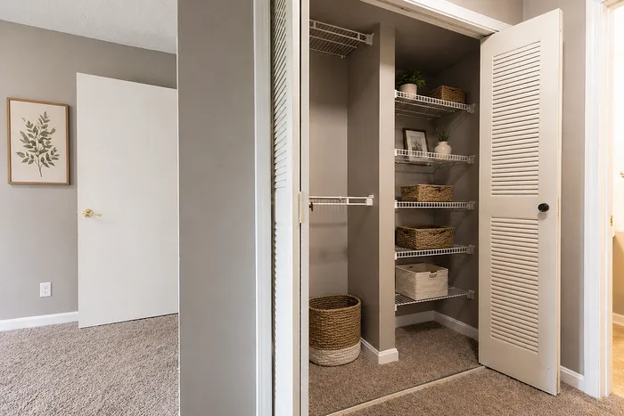 Modern apartment closet with stylish shelving, woven baskets, and natural decor, creating an organized and inviting space.