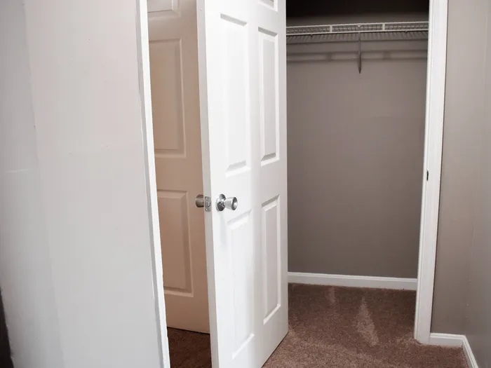 Spacious walk-in closet with ample shelving and modern white door, perfect for storage.