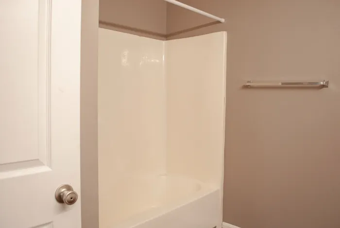 Modern bathroom featuring a sleek bathtub, neutral toned walls, and a stylish towel bar.