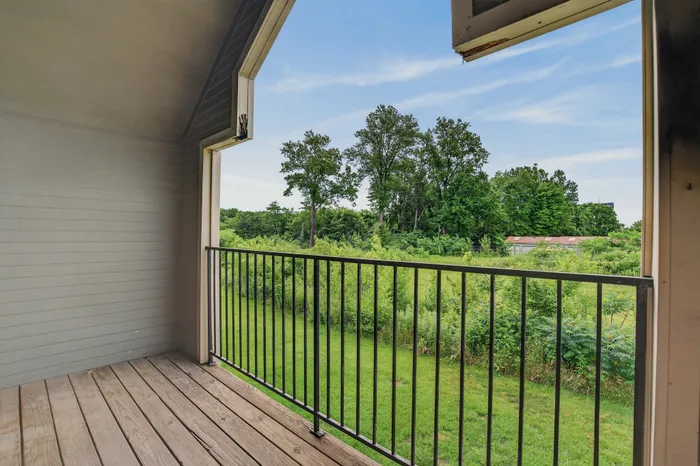 Charming balcony offering a serene view of lush greenery and blue skies, perfect for relaxation.
