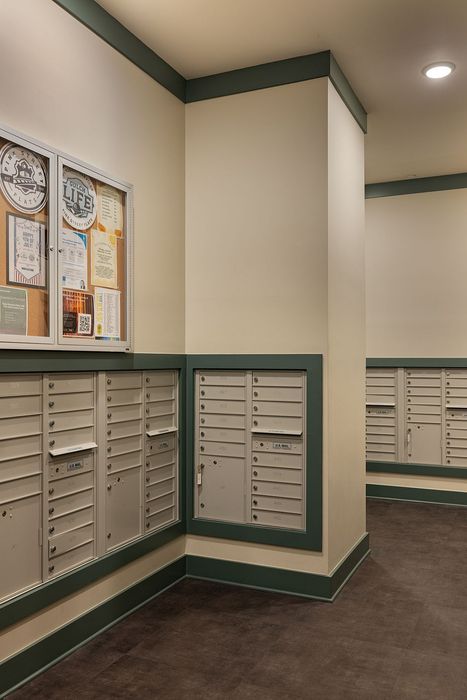 Elegant apartment mailroom with a modern design, featuring organized mailboxes and a sleek information board.