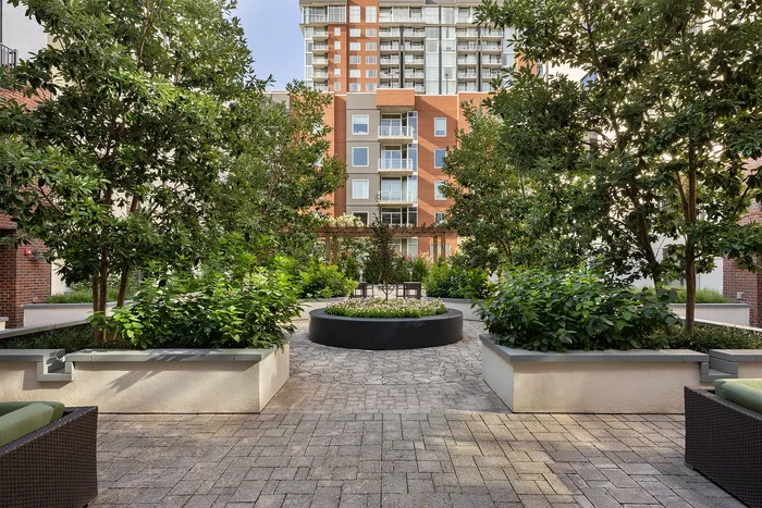 Elegant courtyard with lush greenery and modern apartment building backdrop, perfect for relaxation.