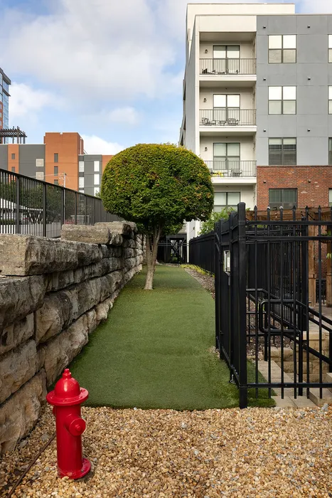 Charming urban apartment with modern facade, lush greenery, and secure fencing, ideal for city living.