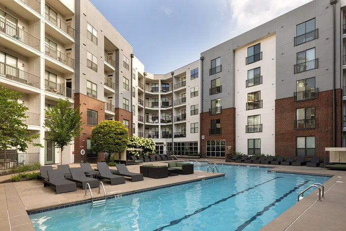 Modern apartment complex with spacious outdoor pool and stylish lounge chairs, offering a luxurious lifestyle experience.