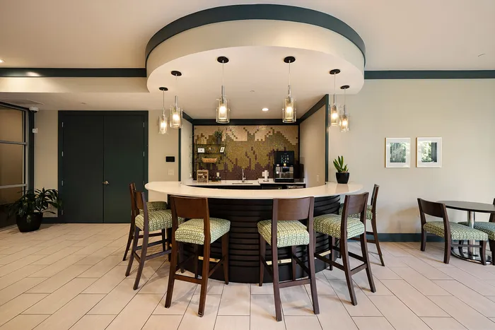 Inviting modern lounge area with elegant lighting, curved bar seating, and chic decor, perfect for relaxation and socializing.