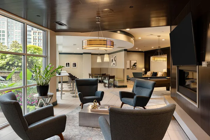 Luxurious apartment lounge showcasing elegant seating, modern decor, and a vibrant view through expansive windows.