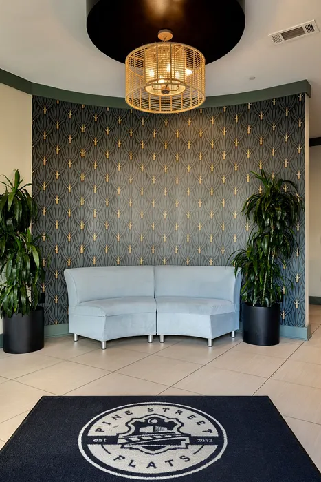 Stylish lobby at Pine Street Flats featuring elegant wallpaper, a chic curved sofa, and vibrant plants for a welcoming atmosphere.