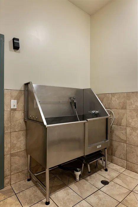 Sleek industrial-style washing station with modern stainless steel sink and elegant tile flooring, perfect for functional utility spaces.