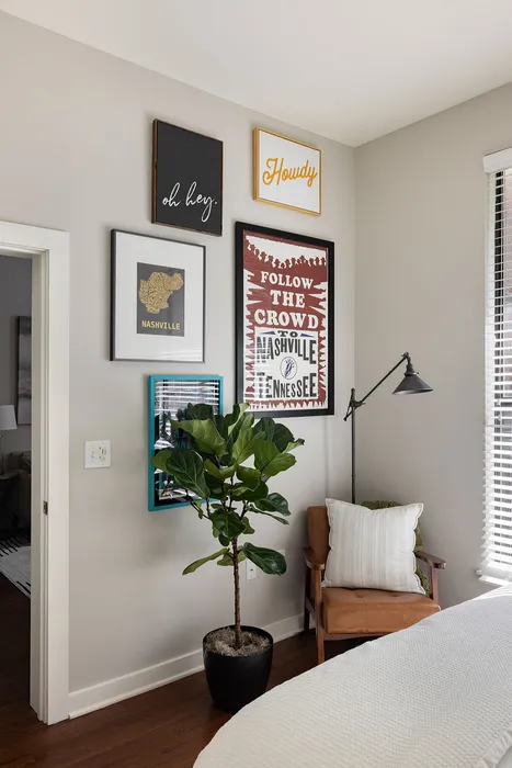 Cozy room corner with stylish wall art, a plush armchair, and a vibrant potted plant, exuding a warm Nashville vibe.