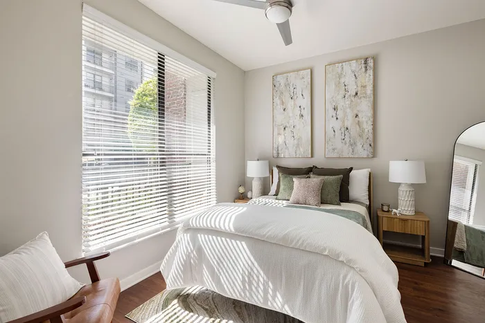 Elegantly designed bedroom featuring modern art, neutral tones, and abundant natural light through large windows.
