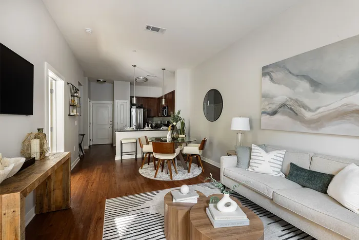Contemporary living room and kitchen area with stylish decor, featuring a cozy sofa, elegant round dining table, and modern pendant lights.