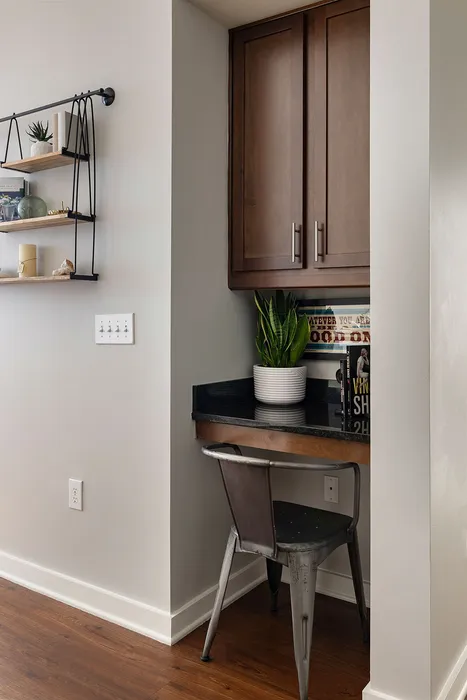 Charming home office nook featuring sleek wooden cabinets, a modern metal chair, and stylish shelving with decor, perfect for a cozy workspace.