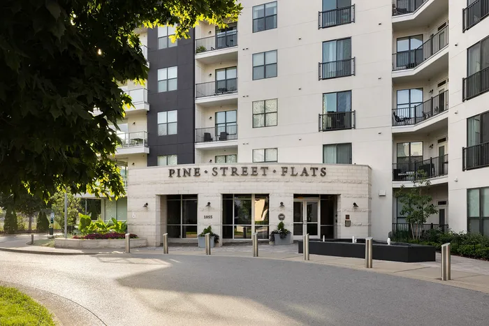 Elegant exterior of Pine Street Flats with modern balconies and lush landscaping, offering stylish urban living.