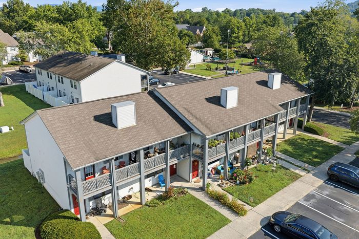Charming apartment complex with spacious balconies, surrounded by lush greenery and a vibrant community setting.