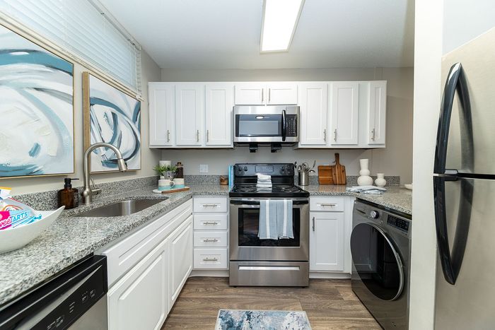 Contemporary kitchen featuring sleek stainless steel appliances, elegant granite countertops, and stylish white cabinetry.