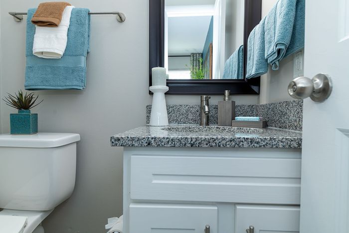 Chic bathroom with sleek granite countertop, modern fixtures, and a fresh blue towel set for a serene ambiance.