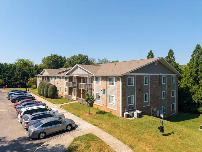 Charming apartment complex with ample parking, lush green surroundings, and stylish two-story design.