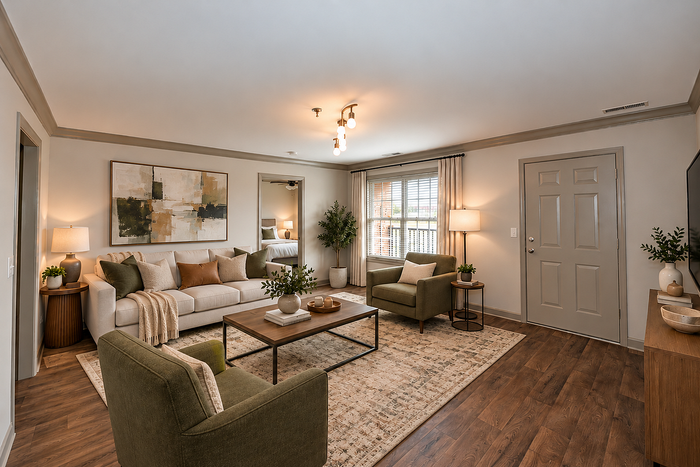 Modern living room with elegant decor, featuring a plush sofa, stylish armchairs, wooden coffee table, and ambient lighting. Natural light streams through large windows, highlighting the warm tones and tasteful artwork.