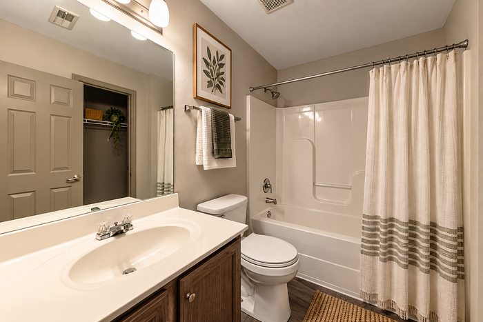 Elegant bathroom with a sleek white vanity, modern fixtures, and a pristine bathtub accented by a stylish shower curtain.