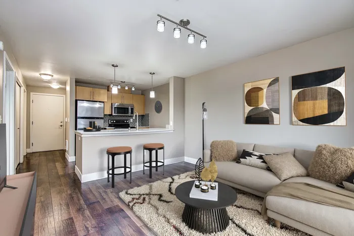 a living room filled with furniture and a kitchen with stainless steel appliances