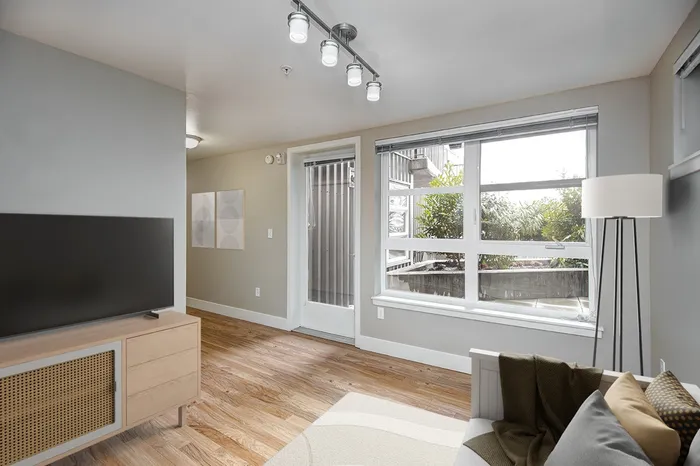 a Livingroom with a couch, TV stand, and television in it. with large windows