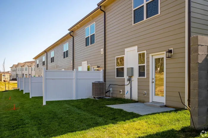 Exterior shot of back of townhomes with white paneling and patios in the day time