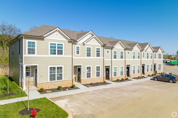 Exterior shot of townhomes with tan paneling and brick in the day time