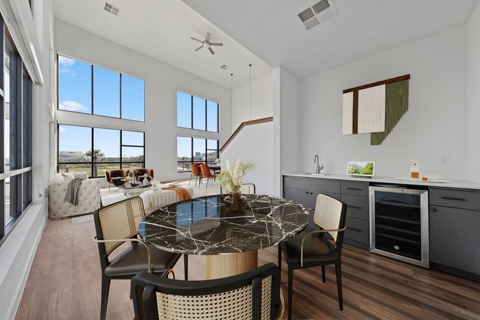 Callia dining room facing living room, cabinets with stainless steel drink fridge, small sink, wall decor