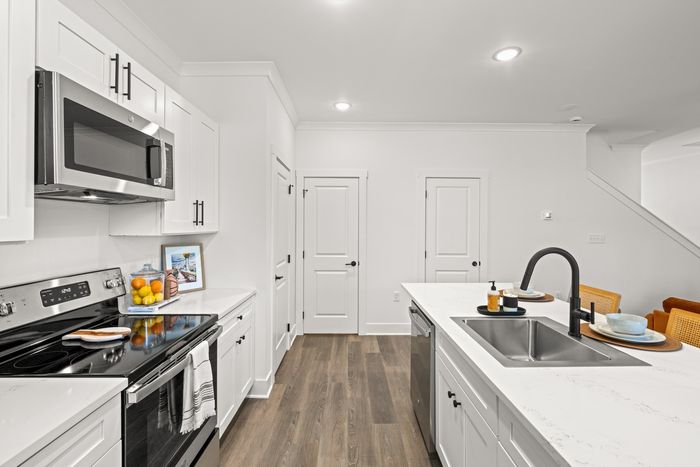 Kitchen with hardwood style flooring, stainless steel applicances and white cabinets