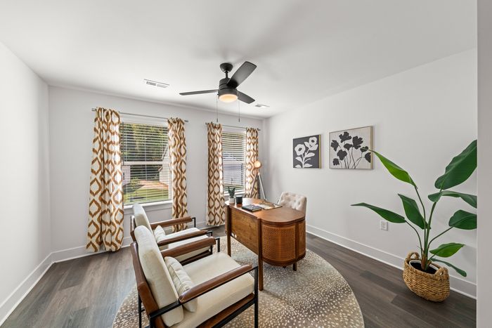 furnished office space with two windows, lighted ceiling fan, desk and sitting chairs