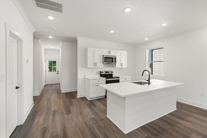 Unfirnished kitchen with stainless steel and black appliances and white cabinets and kitchen island
