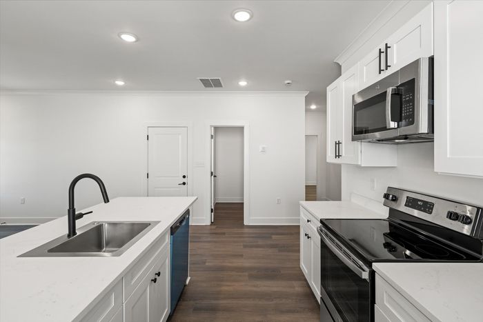 Kitchen with stainless steel and black appliances and white cabinets