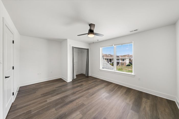 Unfurnished bedroom with one window, hardwood style flooring and lighted ceiling fan