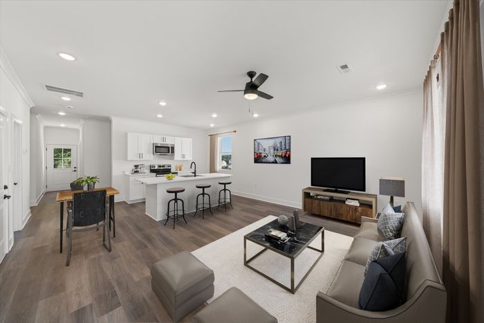A bright living area with a couch, large windows, and a kitchen with a kitchen island and stainless steel appliances at Highline at Knoxville houses for lease in Knoxville, TN