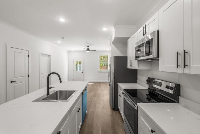 Kitchen with stainless steel and black appliances and white cabinets