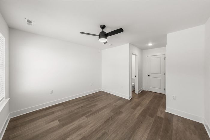 Unfurnished bedroom with window, hardwood style flooring, and lighted ceiling fan